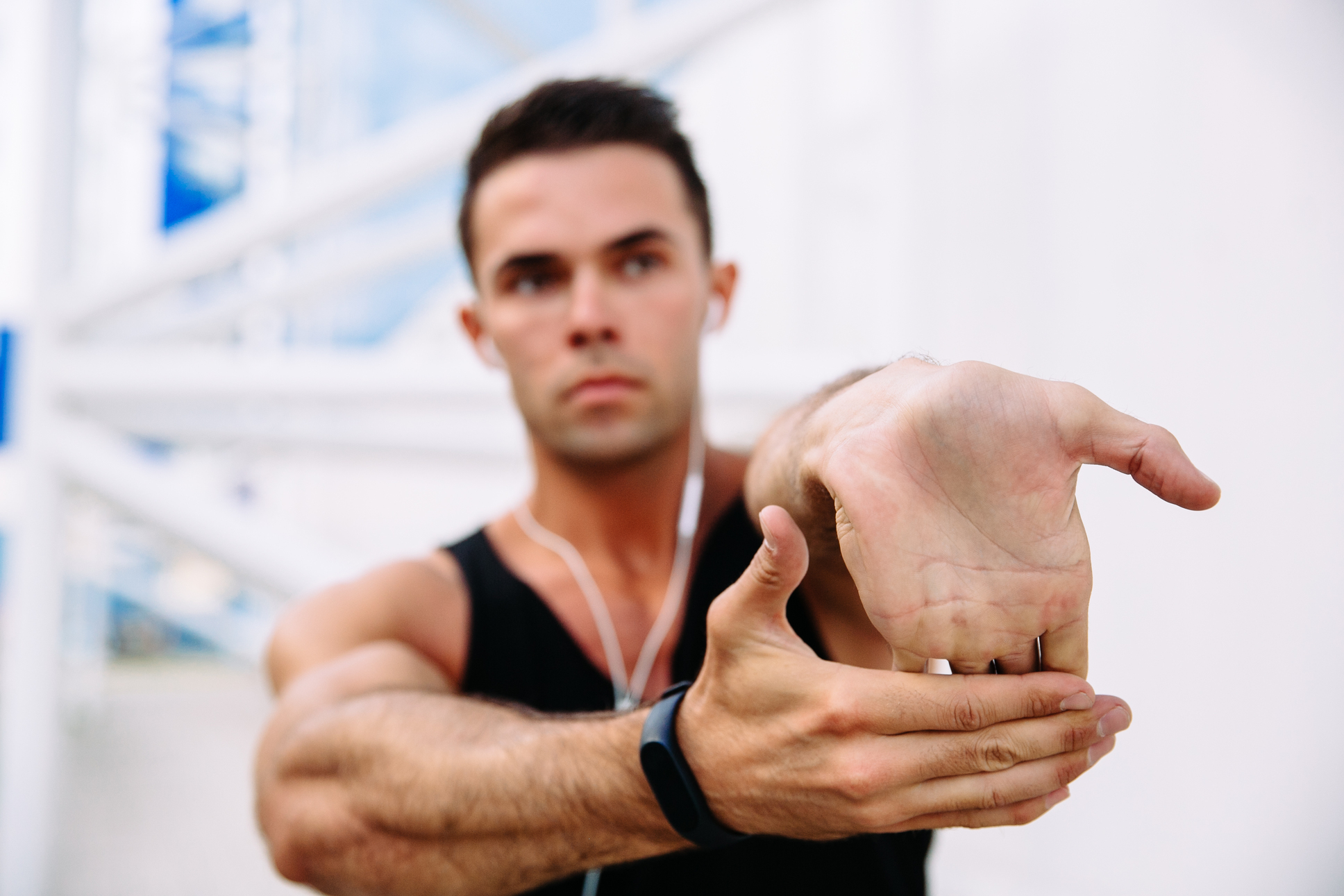 Man gently stretching his wrist by pressing the fingers of one hand back with the other
