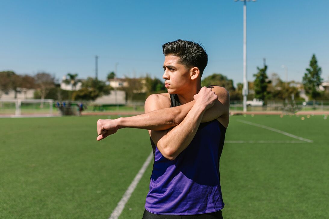 Man outdoors pulling one straight arm across his chest with the other arm